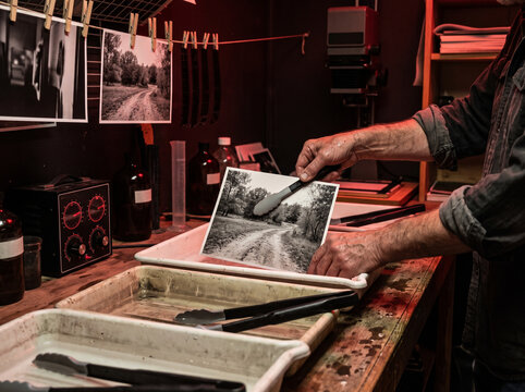 Professional photographer processing black and white photos in darkroom studio