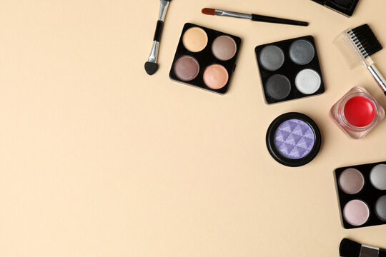 Cosmetics and makeup brushes on a beige background, essential beauty and skincare products, flat lay composition.
