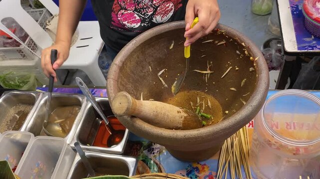 Vendor Mixing Sauce For Fresh & Spicy Thai Papaya Salad (Som Tum), Cuts Tomato in Mortar & Pestle. Asian Street Food Open Night Bazaar Market, Bangkok Thailand