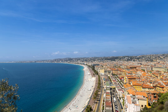Aerial view of the Mediterranean coastline, the historic city center with terracotta rooftops, and the Promenade des Anglais in Nice, Provence-Alpes-Cote d'Azur, France.