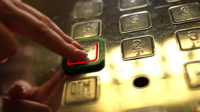 Low-angle view of woman hand pushing first floor button on metallic elevator control panel with braille symbols for visually impaired, selected button lighting up with red glow in slow motion.