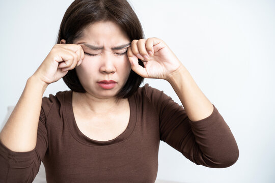 Asian woman rubbing her painful itchy eyes, suffering from eye fatigue, allergies, dry eye syndrome, infection, or vision strain