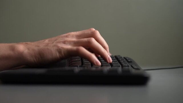 Close-up of male hand typing on black computer keyboard. Fingers press keys quickly. Concept of office work, programming, writing, communication, data entry. Shooting in slow motion.