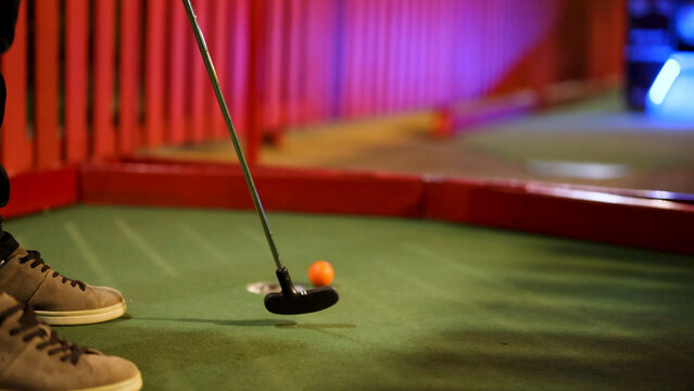 Close-Up of a Mini Golf Putter and Orange Ball on Green Carpet