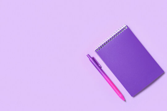 Purple spiral notebook and pen on a light lavender background with copy space, top view