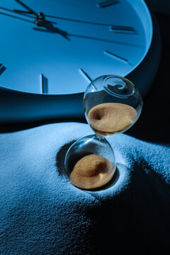 Hourglass with sand flowing on a blue sand dune, Time passing and deadline concept, clock