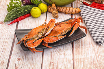 Cooked crabs on black plate with fresh vegetables and spices on rustic wood table © Andrei Starostin