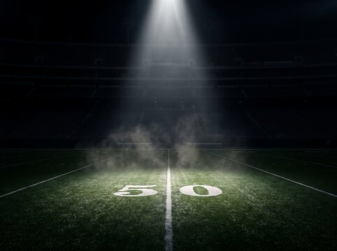 Illuminated football field with glowing fifty yard line under stadium lights