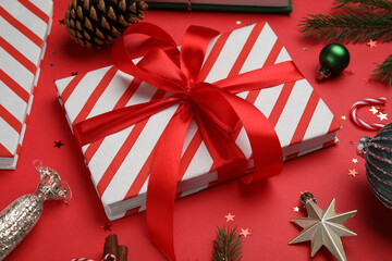 Fototapeta premium Composition with book, Christmas decor and confetti on red background, closeup