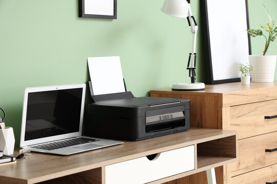 Workplace with modern printer and laptop in stylish home office, closeup