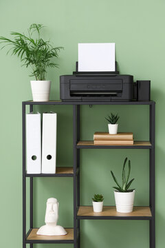 Shelving unit with modern printer, houseplants and decor in stylish home office