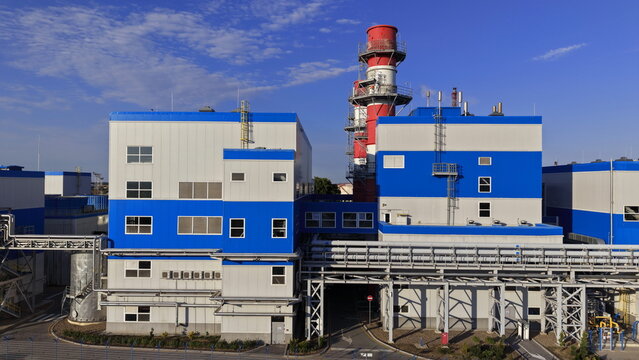 Aerial view of the industrial facility with blue and white buildings, tall chimneys, and complex piping systems in the south industrial zone of Pancevo, Serbia.