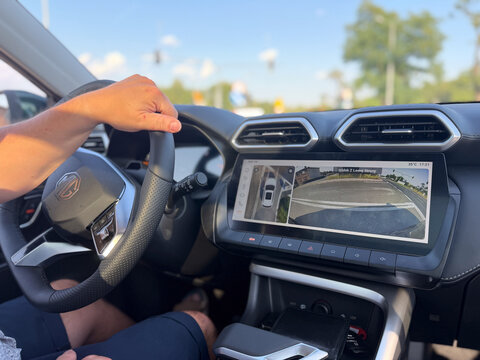 Driver hand on steering wheel inside modern car with dashboard screen showing backup camera view while reversing MG S5 EV electric Poland, Pszczyna, 3.08.2026 
