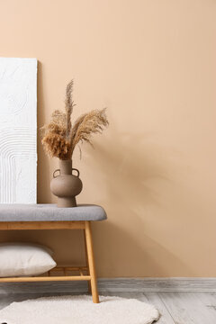 Interior of stylish room with soft bench near beige wall
