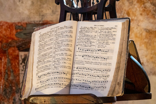 Open Latin hymnal with Gregorian chant resting on wooden church lectern.