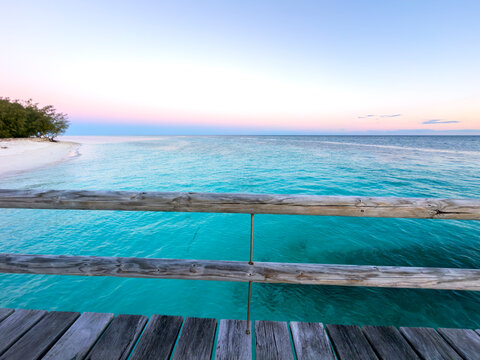 Turquoise ocean and white sandy shore beneath a pastel sunset sky at Heron Island, Queensland, Australia.