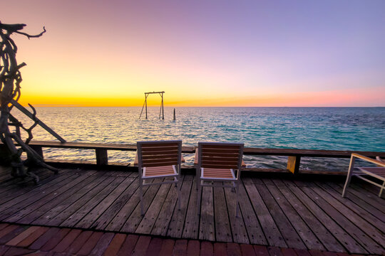 Two chairs overlooking the ocean during a golden sunset at Heron Island, Queensland, Australia.
