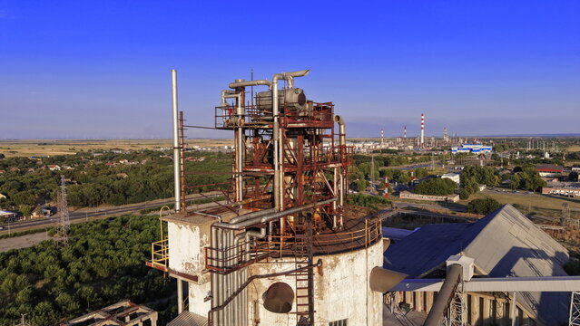 Aerial view of the industrial facility in the south industrial zone with rusty metal structures, pipes, and concrete towers surrounded by greenery in Pancevo, Serbia.
