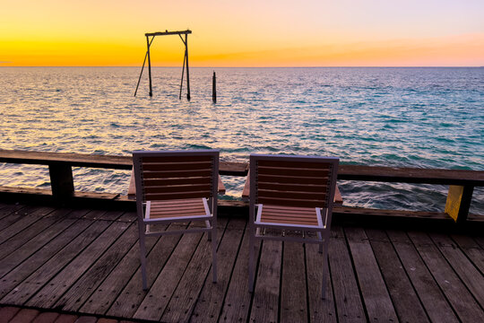 Two chairs overlooking the ocean during a golden sunset at Heron Island, Queensland, Australia.