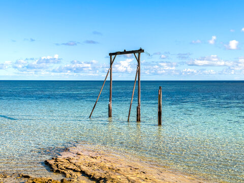 Historic cargo gantry standing in clear shallow water at Heron Island, Queensland, Australia.