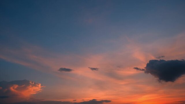 A sunset sky timelapse video showing sweeping cirrus clouds glowing in soft peach and orange tones, contrasted by dark cumulus clouds as the colorful evening light fades across the horizon. 4k.
