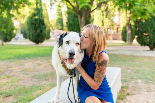 Woman kissing dog showing love and affection in park