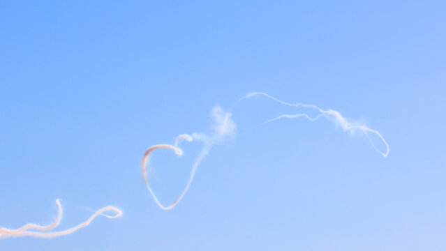 Intricate White Aerobatic Smoke Trails Against a Clear Blue Sky