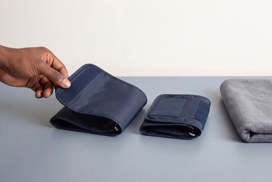 Hand lifting a large fabric arm cuff beside a smaller one, choosing the right size for every body