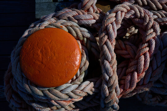 Top view of orange mooring bitt wrapped in thick rope on wooden vessel deck, Gdynia, Pomerania, Poland, Baltic Sea, Europe