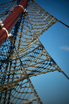 Low angle view of rope netting and wooden mast rigging against blue sky, Gdynia, Pomerania, Poland, Europe