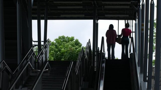 Silhouette Figure Walking Down Escalator Through Steel Beam Skytrain Structure