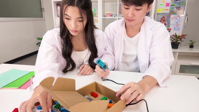 Thai Students in Lab Coats Building Science Project with Glue Gun