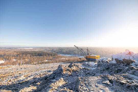 Winter coal mining landscape with excavator in snowy open-pit mine
