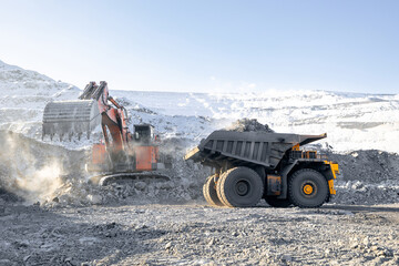 Excavator loads coal into large yellow dump truck on open pit mine. Industry mining on winter career © Parilov