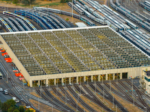 Aerial view of the train depot in the EUR district, featuring rows of parked trains and a large industrial maintenance facility in Rome, Lazio, Italy.