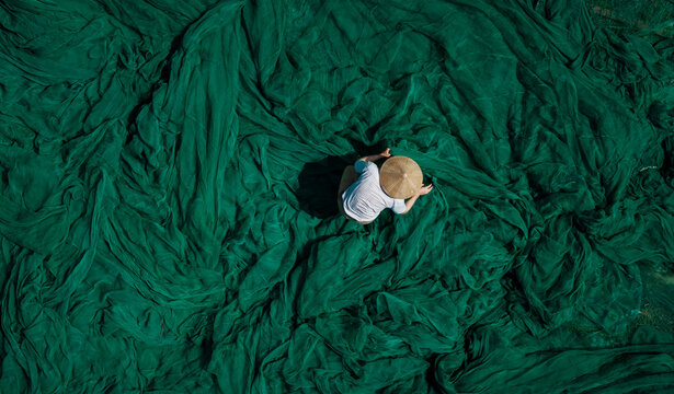 Male worker sorting green fishing nets in Vietnam aerial view