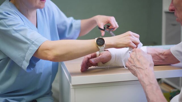 Medical professional carefully unwraps bandage from senior man hand. Nurse assists recovery patient with gentle care in sterile clinic setting. Healing process brings relief and hope to patient