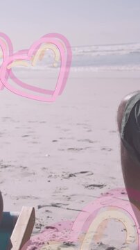 Animation of hearts over senior african american couple lying on sunbeds on sunny beach