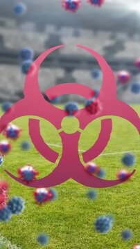 Biohazard symbol and Covid-19 cells against empty sports stadium