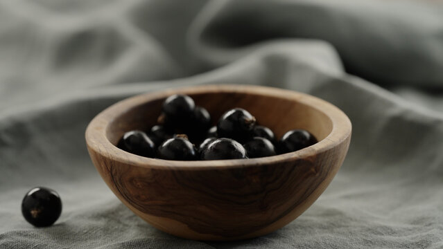 ripe blackcurrant falling in wood bowl