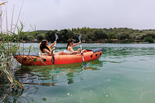 Young women kayaking on tranquil lake during summer vacation