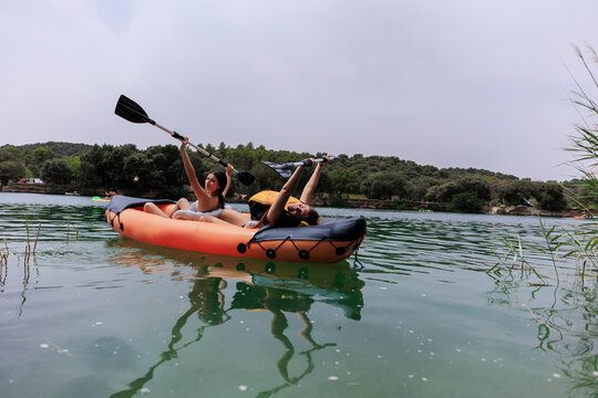 Two young women enjoying kayaking on lake during summer vacation