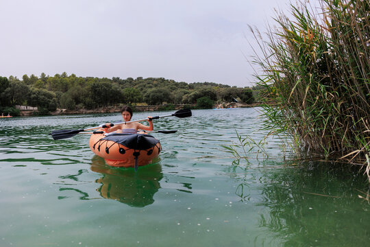 Young woman paddling inflatable kayak enjoying water sports