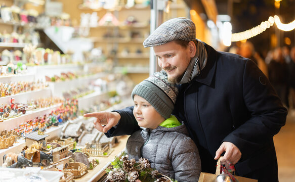 Father and son visited a Christmas market and look at the figurines to create a nativity scene.