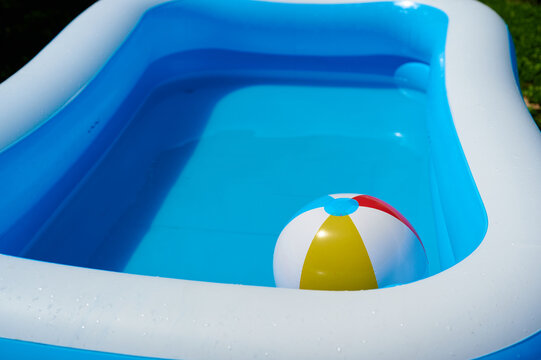 An inflatable blue and white children paddling pool with a colorful beach ball