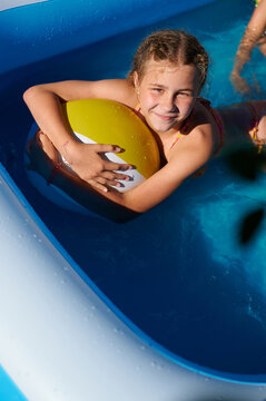 Happy girl playing with a beach ball in a swimming pool