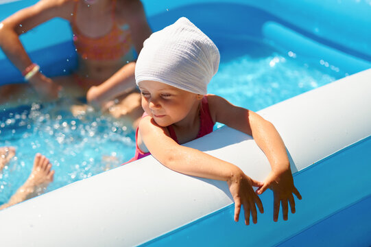 Happy toddler girl enjoying summer day in inflatable swimming pool