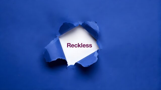 The word reckless written on a white paper revealed through a torn blue paper background