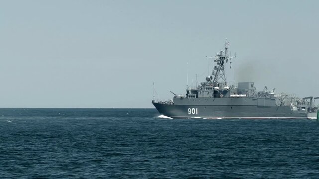 Russian navy minesweeper ship sailing across calm blue sea under bright clear sky in daylight action shot.