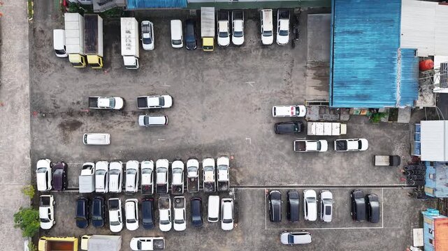 The parking lot was filled with cars lined up for rent, and there were several cars damaged in accidents parked there.